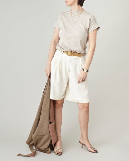 Model wearing raw silk Bermuda shorts styled with a minimalist beige top