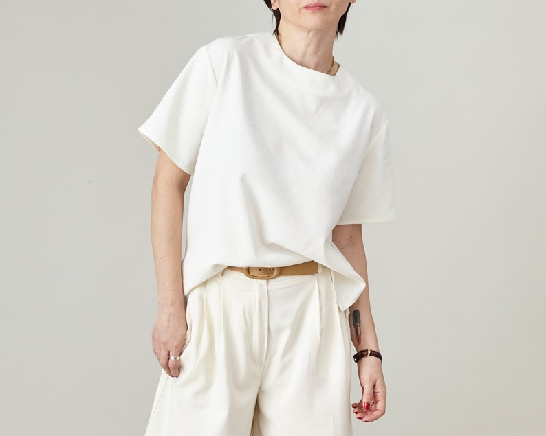 Person wearing a white top and matching 
pants on a plain background