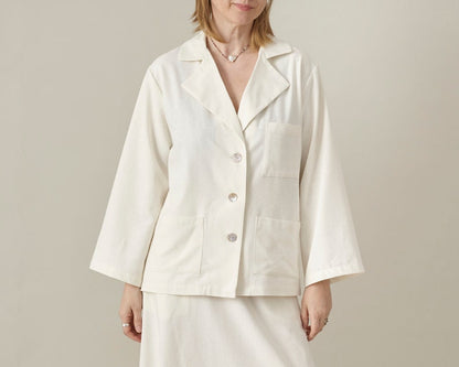 Woman wearing a white patch pockets blouse against a plain background
