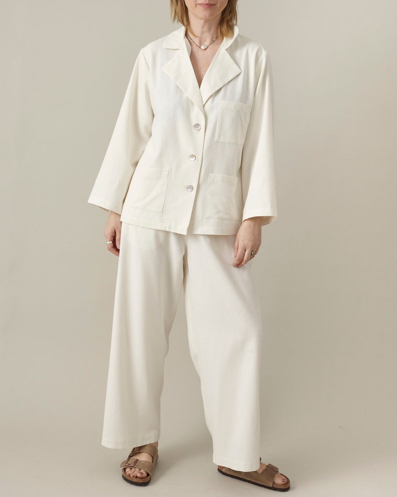 Person wearing a white matching set  with oversized blouse and wide leg pants on a plain background