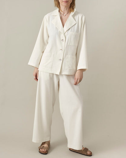 Person wearing a white matching set  with oversized blouse and wide leg pants on a plain background