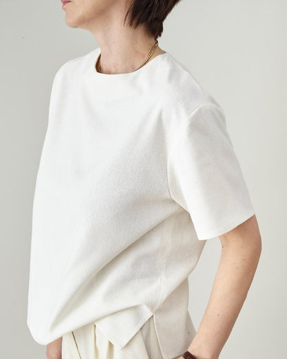 Person wearing a white top with a plain background