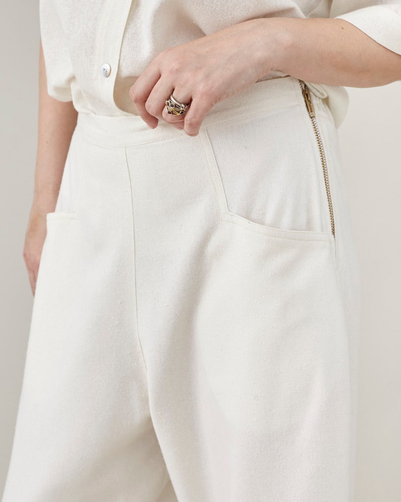 Close-up of a person wearing white pants with a plain background