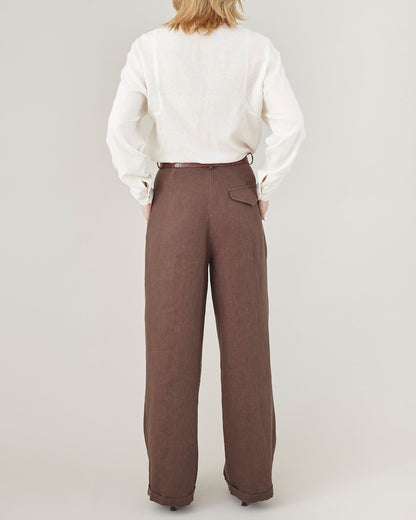 Person wearing a white shirt and brown pants on a plain background