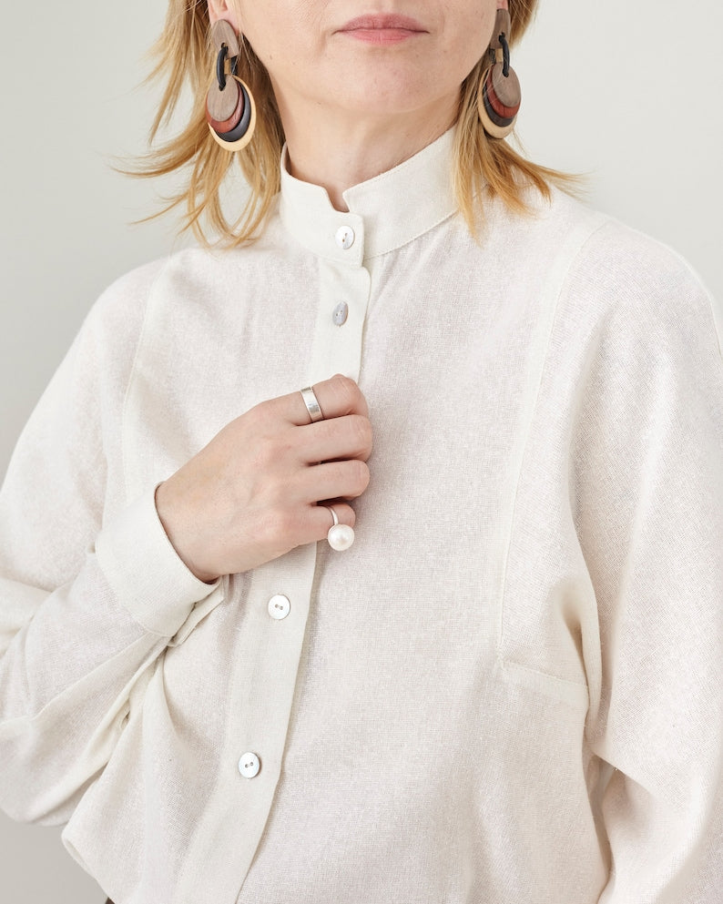 Person wearing a white button-up shirt with a neutral background