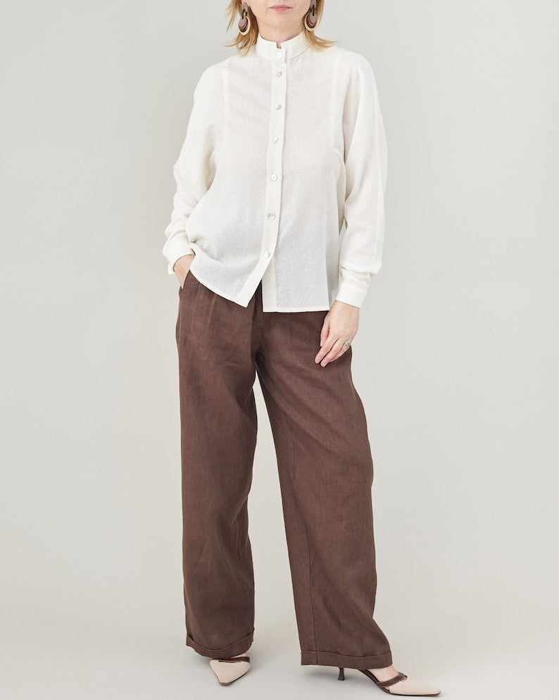 Person wearing a white blouse and brown pants on a plain background