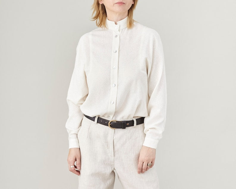 Person wearing a white button-up shirt and beige pants on a plain background