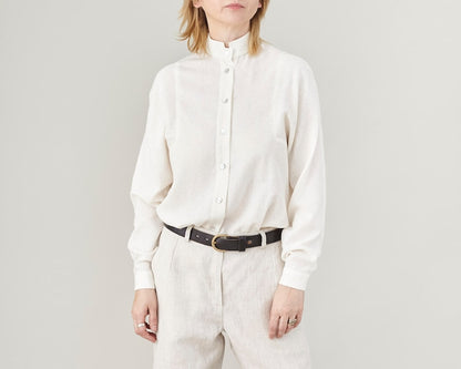 Person wearing a white button-up shirt and beige pants on a plain background