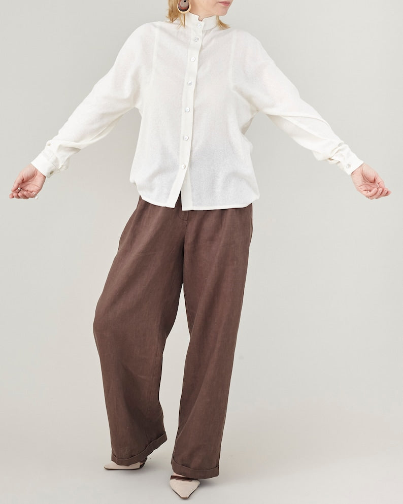 Person wearing a white shirt and brown pants on a plain background