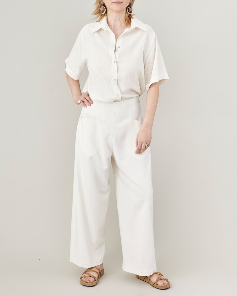 Person wearing a white short sleeve shirt and matching wide-leg pants on a plain background