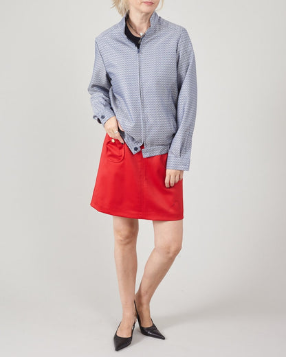 Person wearing a blue patterned shirt and red skirt on a white background