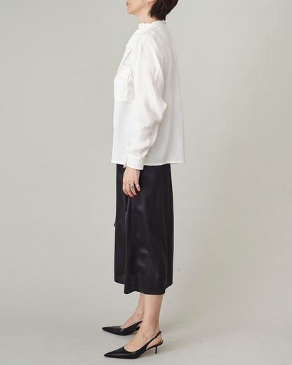 Person wearing a white blouse and black pants on a plain background