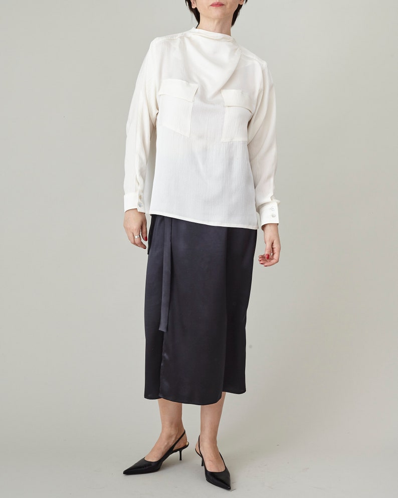 Person wearing a white blouse and black skirt on a plain background