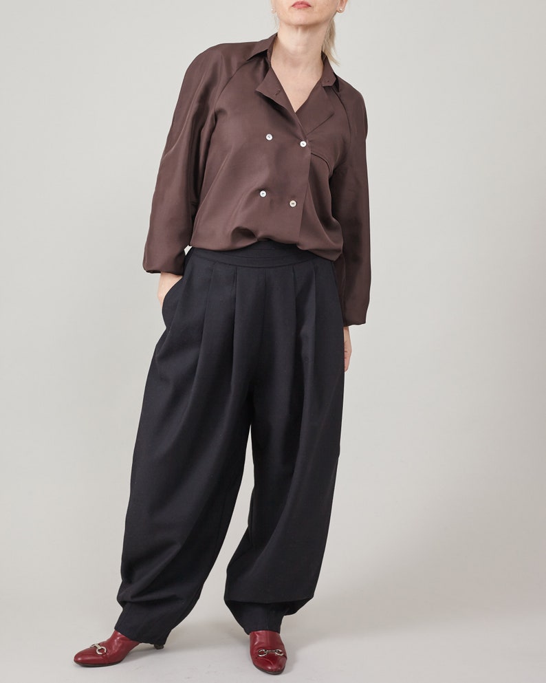 Person wearing a brown shirt and black pants on a plain background