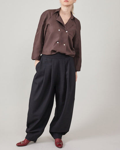 Person wearing a brown shirt and black pants on a plain background