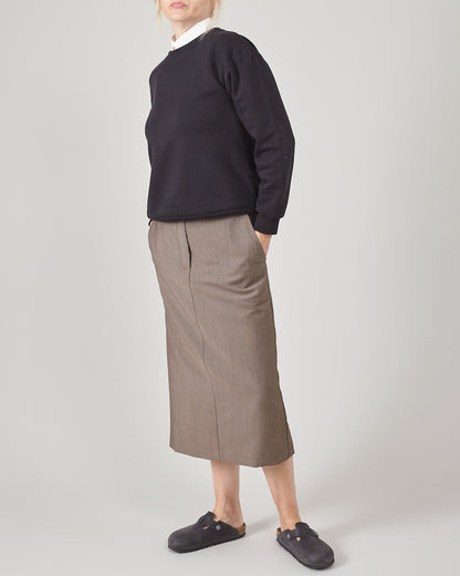 Person wearing a black sweatshirt, greige midi straight skirt and Birkenstock on a white background