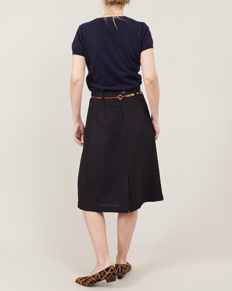Person wearing a navy shirt and black skirt on a plain background