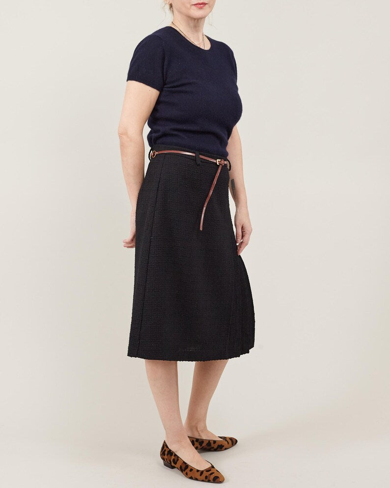 Person wearing a black skirt and navy top on a plain background