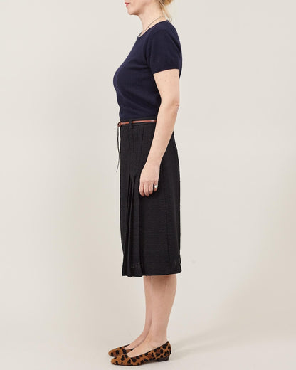 Person wearing a navy top and black skirt on a plain background