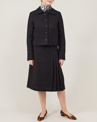 Woman wearing a black suit with a patterned scarf on a white background