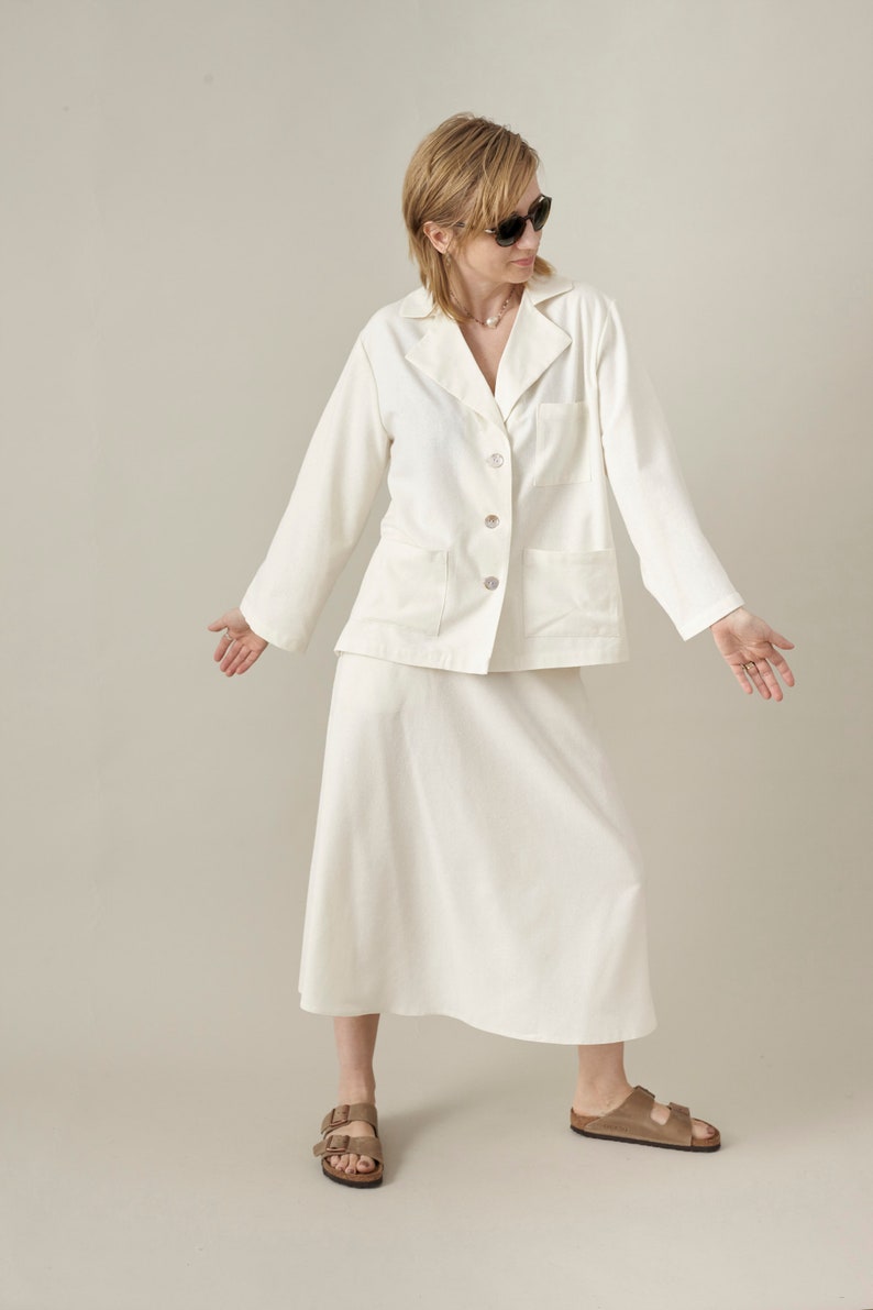 Woman wearing a white outfit with sunglasses on a plain background