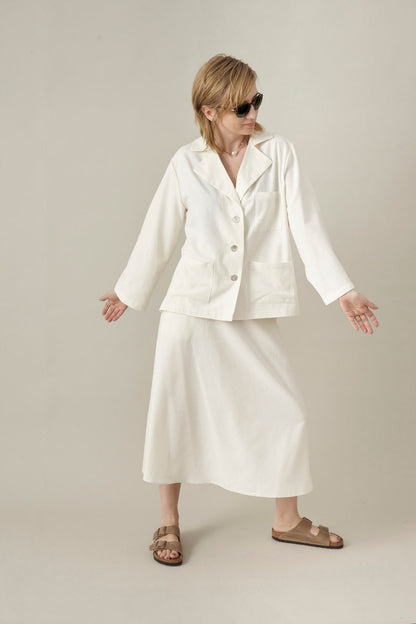 Woman wearing a white outfit with sunglasses on a plain background