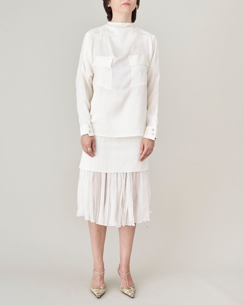 Person wearing a white blouse and skirt set on a plain background