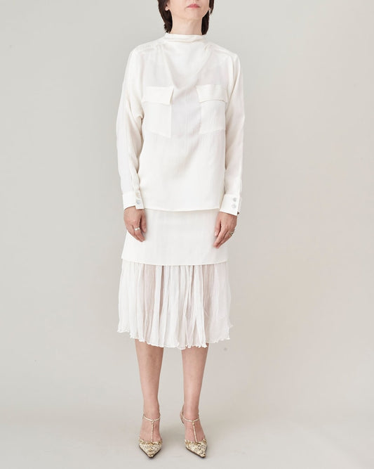 Person wearing a white blouse and skirt set on a plain background