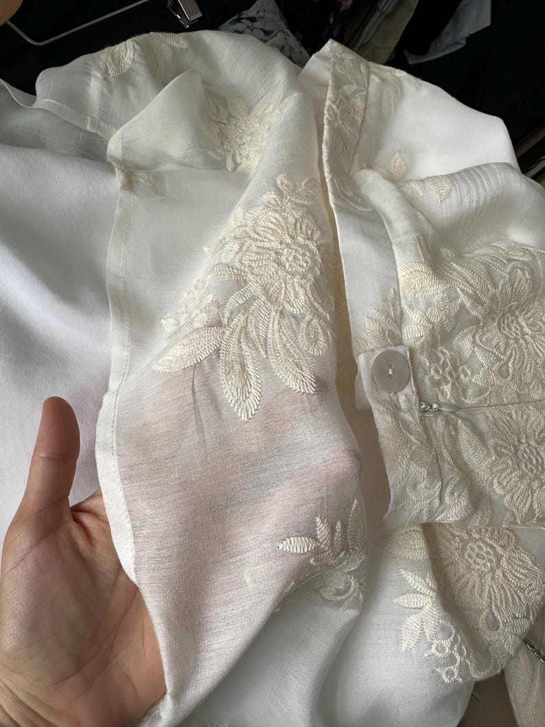 White lace garment held by a hand with a blurred background