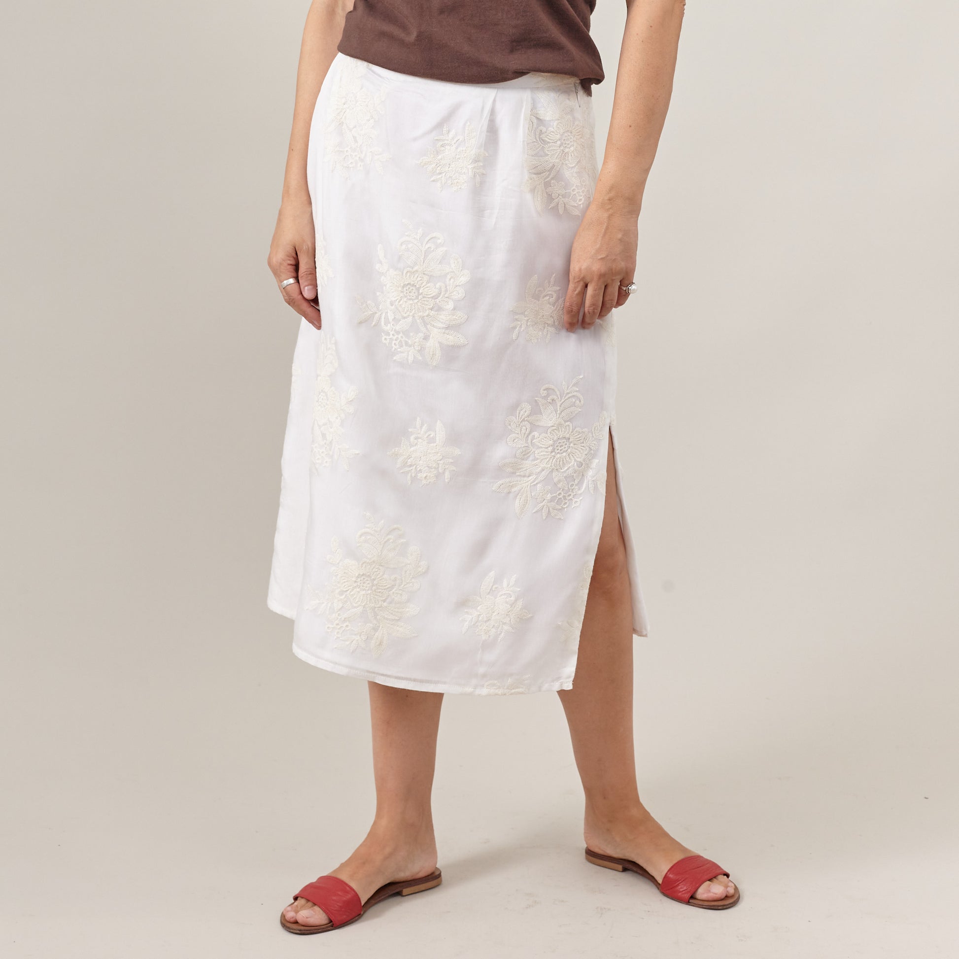 women wearing a white embroidered skirt with brown top and red sandals