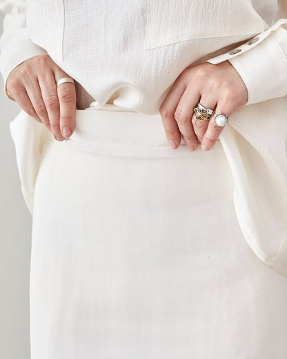 Close-up of hands showing the waist band of a white skirt.