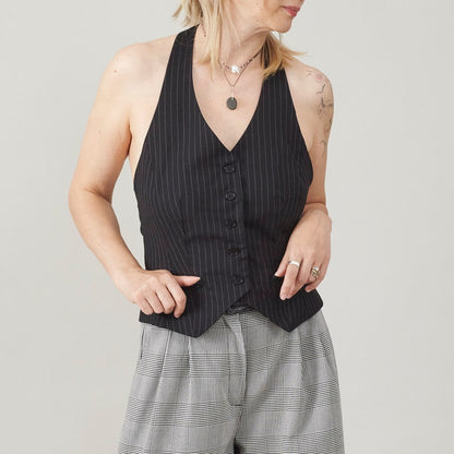Person wearing a black pinstripe vest with plaid pants on a light gray background