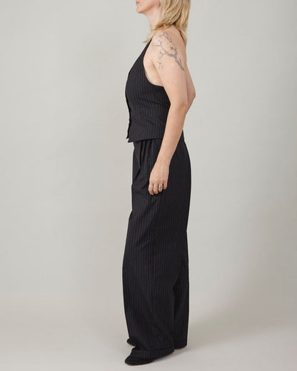 Woman wearing a black vest and wide-leg pants against a plain background